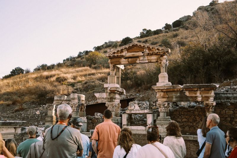 A guided group in sun hats listening in front of the Fountain of Trajan in Ephesus